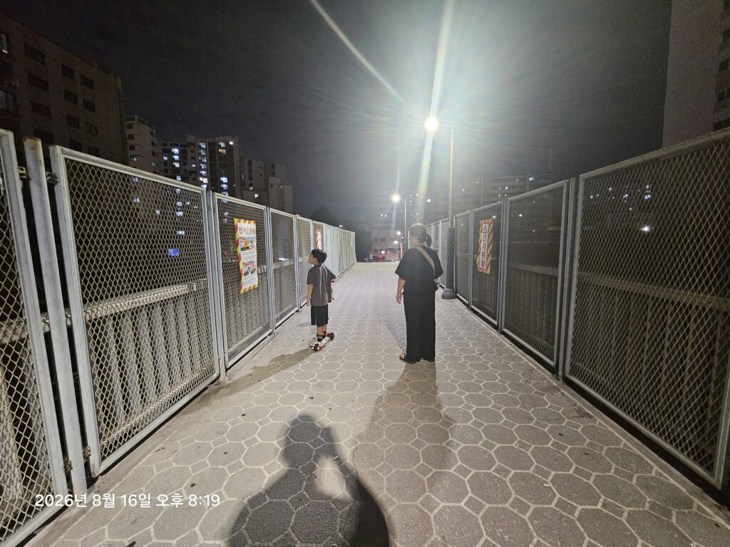 Mother and child walking home at night in a Korean neighborhood